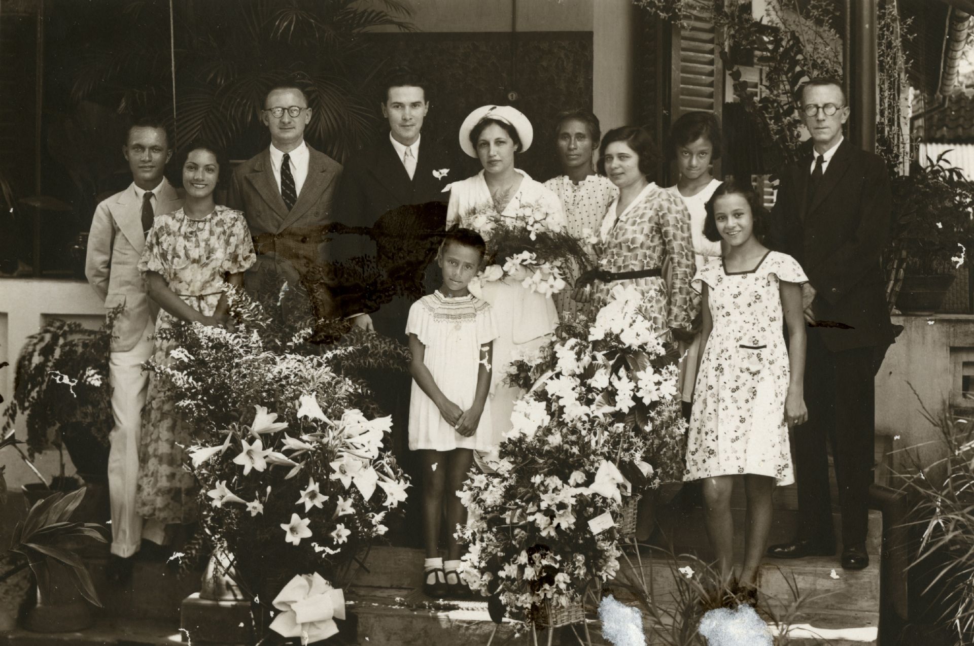 Een foto met een familie en hun bediendes. Allemaal dragen ze Westerse kleding.