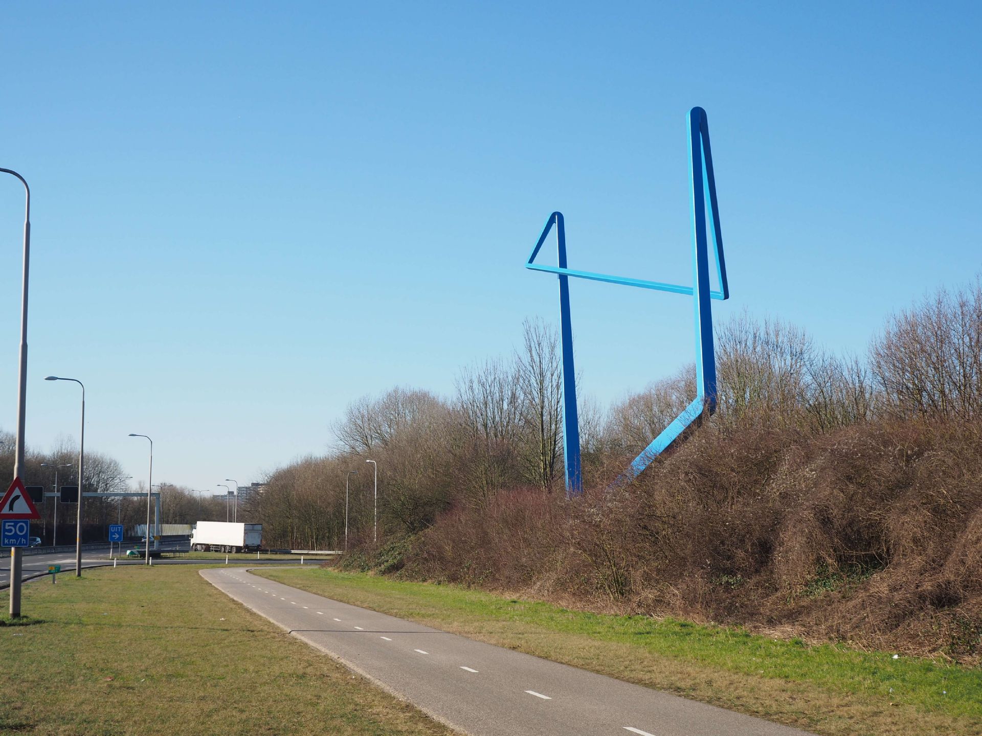 Het kunstwerk staat langs de Pleyroute, precies in een bocht voor of na de brug. Dat maakt het zo bijzonder: het beeld blijft niet hetzelfde, maar verandert steeds van vorm en het lijkt net of het ronddraait. Zo speelt de kunstenaar met de beweging van ons die er langs rijden.